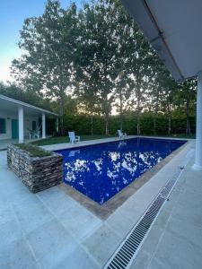 a blue swimming pool with two chairs next to a house at Casa Hotel Villa Sabrosura in Mariquita
