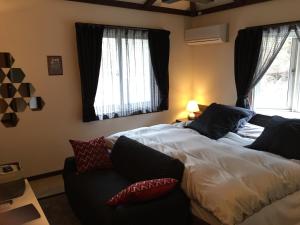 a bedroom with a bed and a couch and windows at 箱根エレガンス in Hakone
