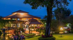 a large house with a tree in the yard at De Bua Valley in Ban Kom