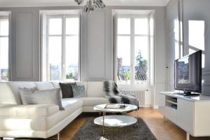 a living room with a white couch and a tv at The Suites in Blaye