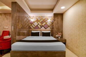 a bedroom with a large bed and a red chair at Super Townhouse Oak Ballygunge Formerly Hotel Lovelock in Ballygunge