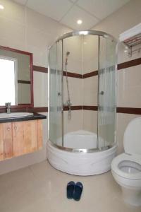 a bathroom with a shower with a toilet and a sink at TVT Hotel in Da Lat