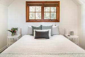 ein Schlafzimmer mit einem großen weißen Bett mit zwei Tischen in der Unterkunft Beautiful 2BR Rainforest Retreat Free Wifi in Springbrook