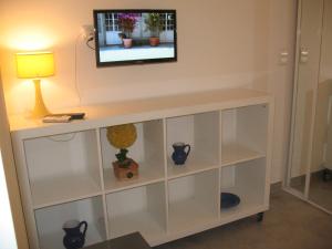 a white entertainment center with a television on a wall at Studio du Lac in Cannes