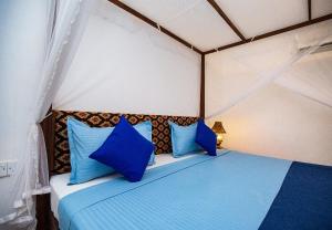 a bedroom with a blue bed with blue pillows at Susu Eco Villa in Talpe