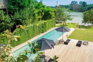 a swimming pool with two umbrellas and chairs and a swimming pool at Phingphayla Photharam in Ban Bang Khayaeng