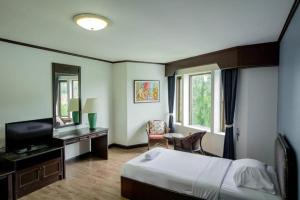 a bedroom with a bed and a desk and a television at Royal Diamond Hotel in Phetchaburi