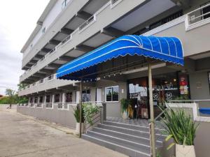 a building with a blue umbrella in front of it at Capital O 75406 Hotel M Rojana in Ban Sang