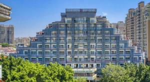 a tall blue building with trees in front of it at Borrman Hotel Zhaoqing Sihui Tianguangxu Jade City in Sihui