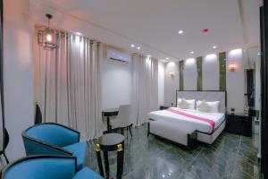 a bedroom with a bed and chairs in a room at La Maison Royale Hotel in Lahore