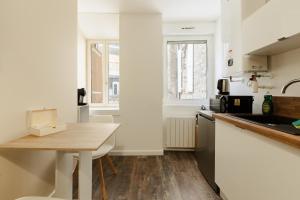 a kitchen with white walls and a wooden table at Le Velours in Valence +6 photos