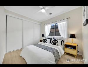 a white bedroom with two beds and a window at Green and sereen home in western suburbs in Truganina