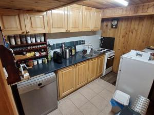 a kitchen with wooden cabinets and a white refrigerator at Chalúpka za Magurou in Matiašovce