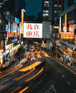 eine belebte Stadtstraße nachts mit Autos in der Unterkunft Chongqing Jiangbei Guanyinqiao Pedestrian Street Berry Hotel in Chongqing