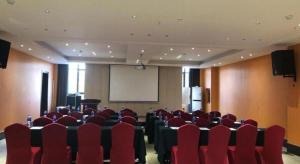 a conference room with red chairs and a white screen at Jinjiang Metropolo Hotel - Liyang Tianmu Lake in Liyang