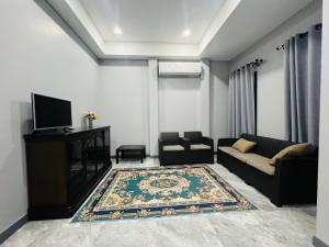 a living room with a couch and a tv at SRE- Holiday Home in Prime Village, Mae Sot 