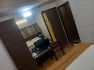 una habitación con una cama, un escritorio y un espejo en hotel Sachin INN, en Etāwah