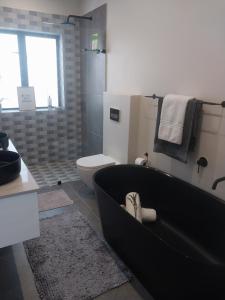 a bathroom with a black bath tub and a toilet at White Feather Wellness Room and Beauty Spa in Yzerfontein