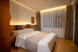 Un dormitorio con una gran cama blanca y una ventana. en Junlan Hotel 张家界郡澜民宿, en Zhangjiajie