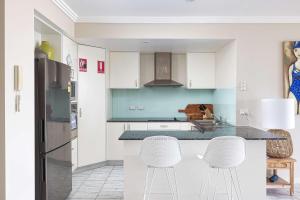 a kitchen with white cabinets and white stools at On the Beach Getaway in One Mile