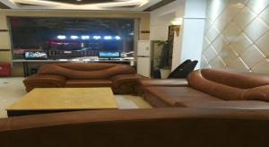 una sala de estar con sofás marrones y una pantalla grande en Shell Suzhou Exhibition Center Huning Chengtie Zone Station Jinfeng Square, en Suzhou