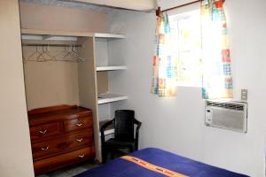 1 dormitorio con 1 cama, vestidor y ventana en Ximenas Guest House, en San Salvador