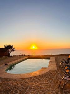 Una piscina con una puesta de sol al fondo en Le calme de la campagne, le souffle de l'océan, en Khemis du Sahel