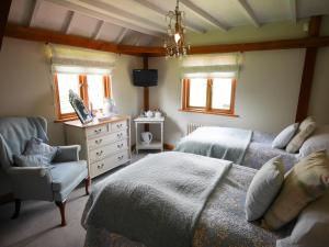 a bedroom with two beds and a chair and a dresser at North Downs Barn in Rochester