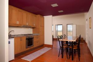a kitchen with wooden cabinets and a table with chairs at Quinta da Gafaria in Santarém