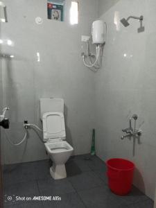 a bathroom with a toilet and a red bucket at Coasta Homestay in Kāsarkod