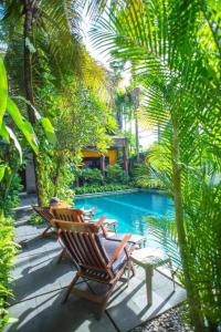 a swimming pool with two chairs and a table next to it at Eclipse Hotel Prawirotaman in Yogyakarta