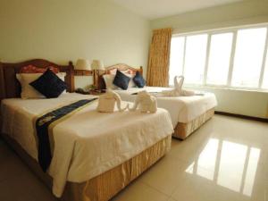 two beds with stuffed animals on them in a bedroom at Midland Hotel in Phnom Penh