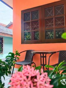 een tafel en stoelen op een veranda met roze bloemen bij Friends Retreat Phuket in Ban Bo Han