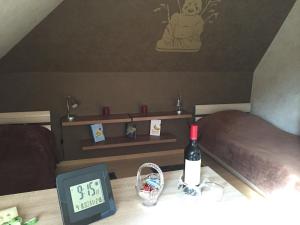 テニングにあるFerienwohnung Geliのベッド2台、時計、ワイン1本が備わる客室です。
