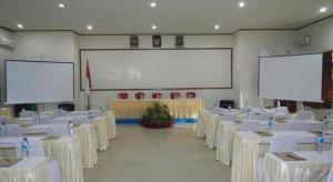 a room with white tables and chairs and a large screen at The Luxio Hotel in Sorong