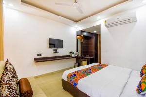 une chambre avec un lit et une télévision au mur dans l'établissement FabHotel City Pride, à Haridwar