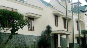 a white building with windows and a stone wall at Bumi Ciherang Hotel in Puncak