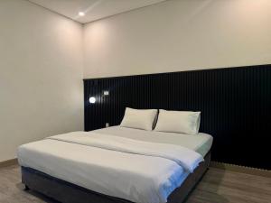 a bedroom with a large bed with white sheets and pillows at Padmara Hotel in Bengkulu