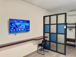 a room with a tv on a wall with a chair at Padmara Hotel in Bengkulu