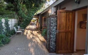 Un edificio con una puerta de madera y sillas en un patio. en MacLeod House, en Bloemfontein