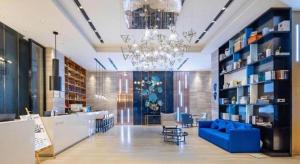a lobby with a blue couch and a chandelier at Echarm Hotel Danzhou Xiari Plaza in Danzhou