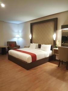 a hotel room with a large bed and a chair at Grand Dian Hotel Slawi in Procot