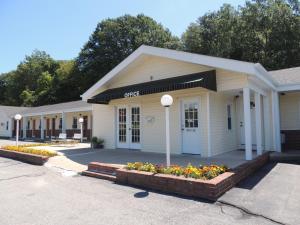 ein weißes Gebäude mit Blumen davor in der Unterkunft Windsor Motel in Groton