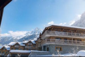 a building in the snow with mountains in the background at Alpine Cocoon at 5 min On foot from the cable car in Les Houches +1 photo