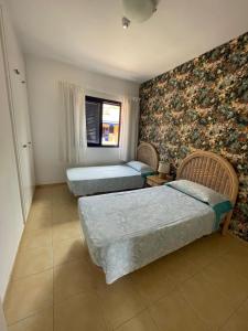three beds in a room with floral wallpaper at Villa Meloneras - Exclusive Chill Out in San Bartolomé de Tirajana