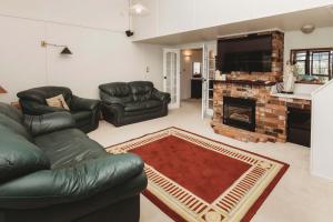 a living room with leather furniture and a fireplace at Family Fun - 4BR home with swimming pool and spa in New Plymouth