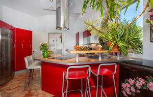 une cuisine avec des placards rouges et des tabourets de bar rouges dans l'établissement Villa Anamia with seaview by Villas Guide, à Šodići