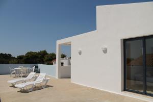 un patio con sillas blancas y mesas en el techo en Villa Romaní Apartament, en Ciutadella