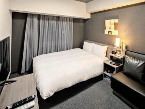 a bedroom with a large white bed and a couch at Hotel Route Inn Matsuyama -Katsuyama Dori- in Matsuyama +23 photos
