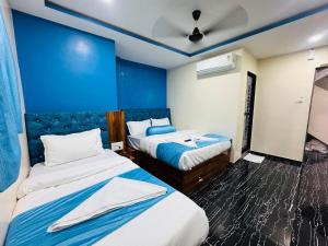 a bedroom with two beds and a blue wall at Hotel Welcome Airoli in Navi Mumbai